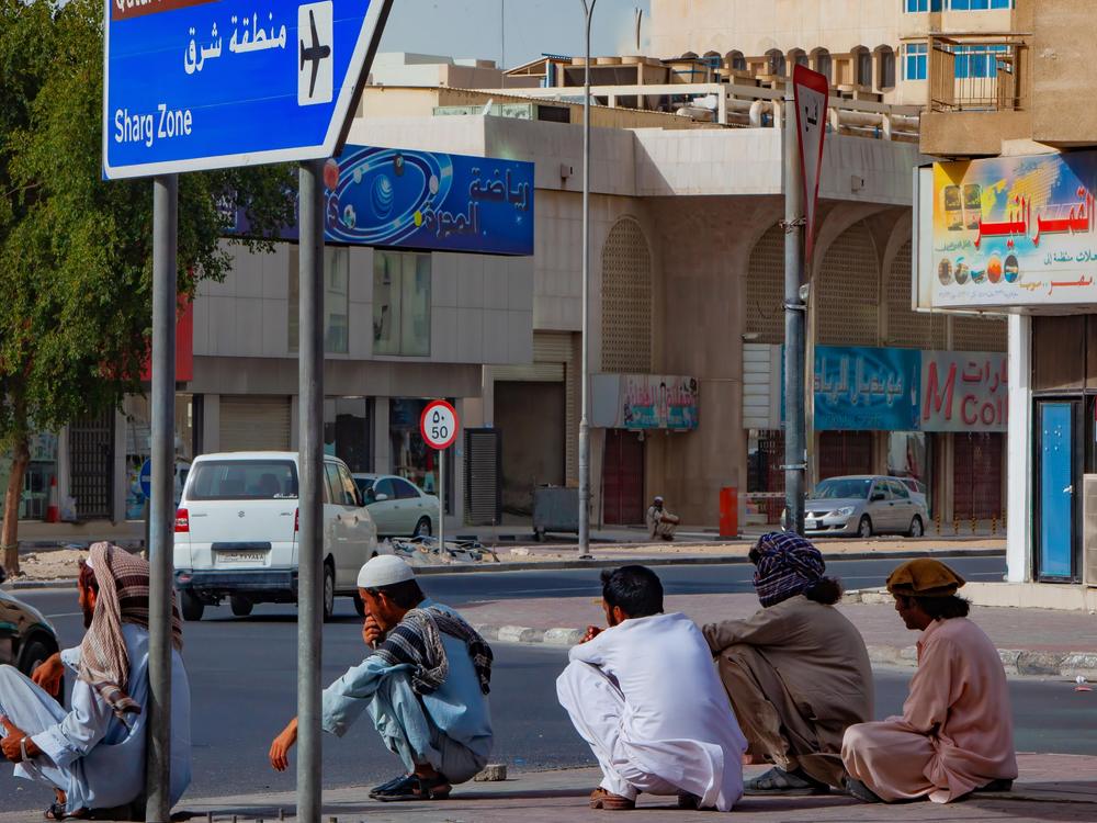 A group of laborers take a break in the warm afternoon on the streets of Doha
