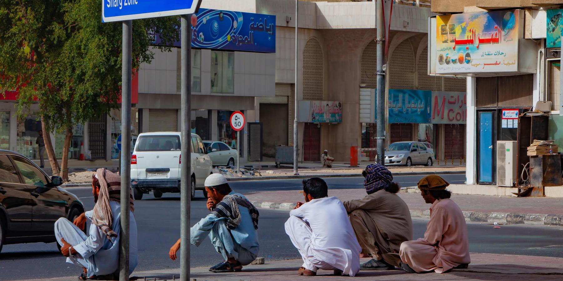 A group of laborers take a break in the warm afternoon on the streets of Doha