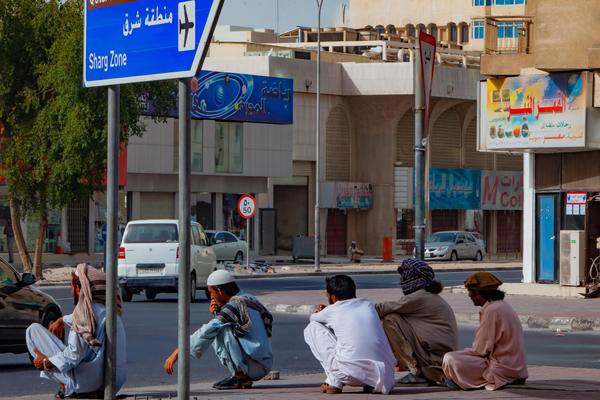 A group of laborers take a break in the warm afternoon on the streets of Doha