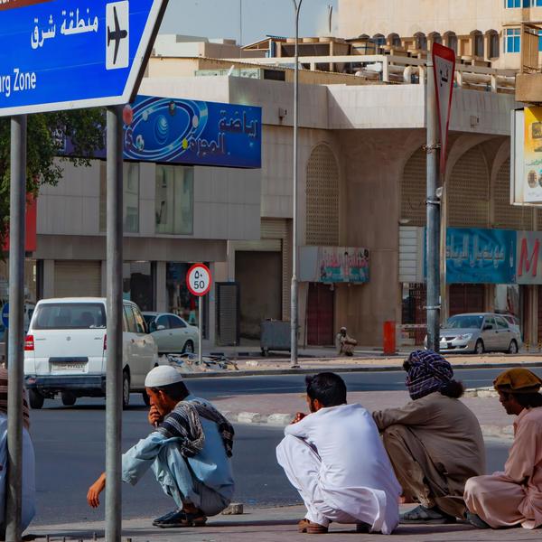 A group of laborers take a break in the warm afternoon on the streets of Doha