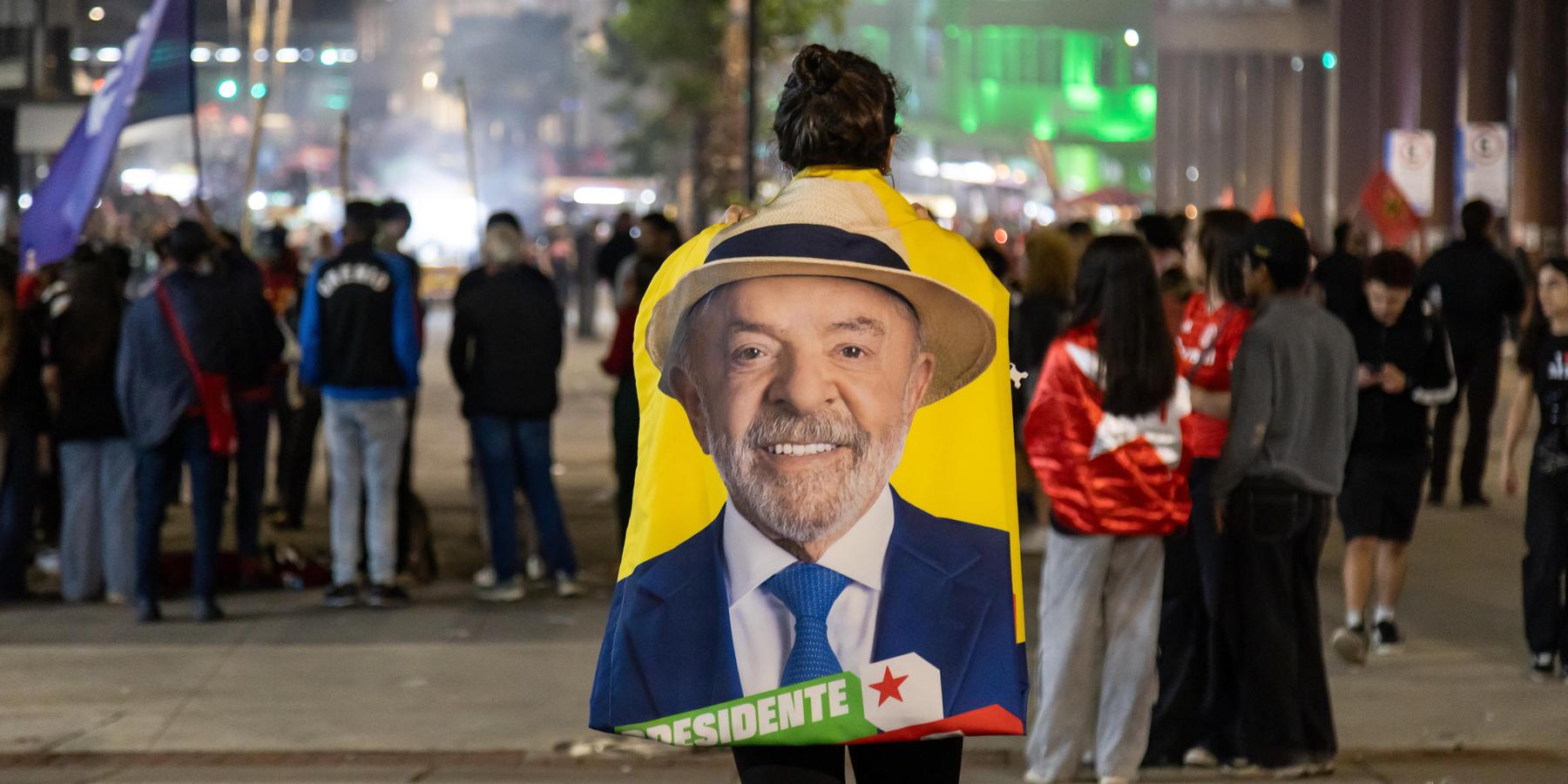 A Lula supporter wears a flag with Lula's image during a PT and Lula campaign rally