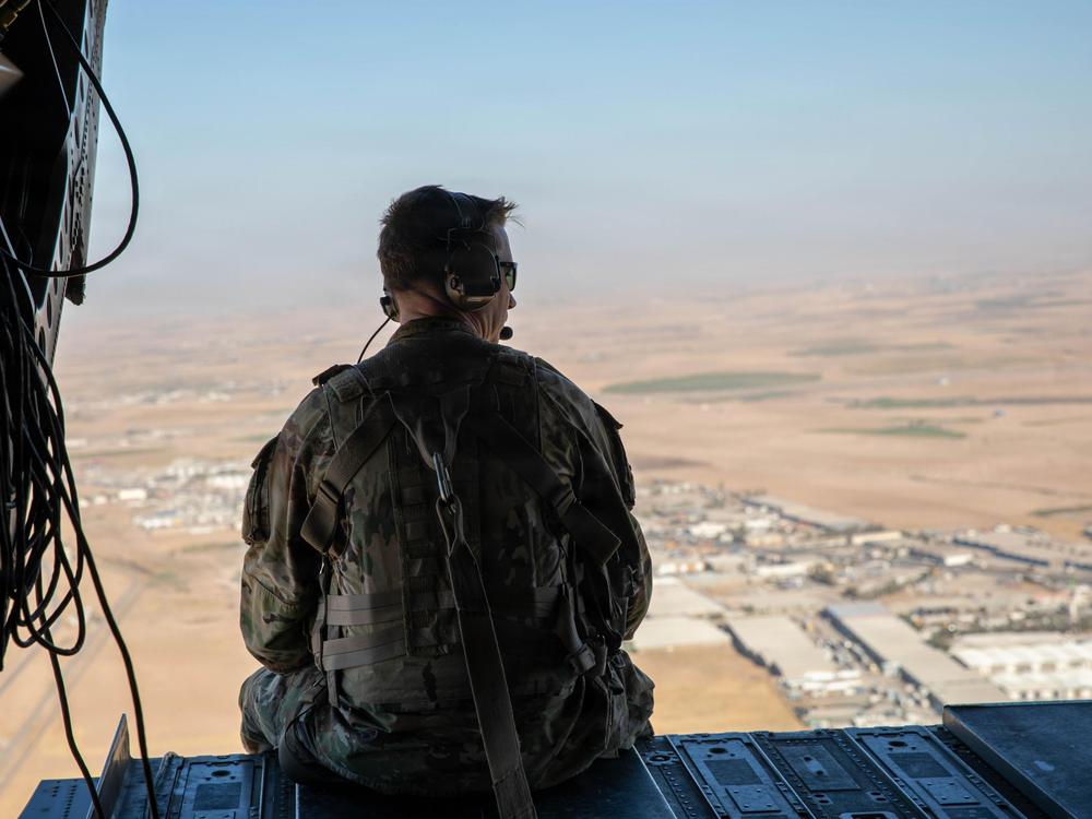 A US soldier sits looking out the back of a CH-47 helicopter as it flies in northern Iraq