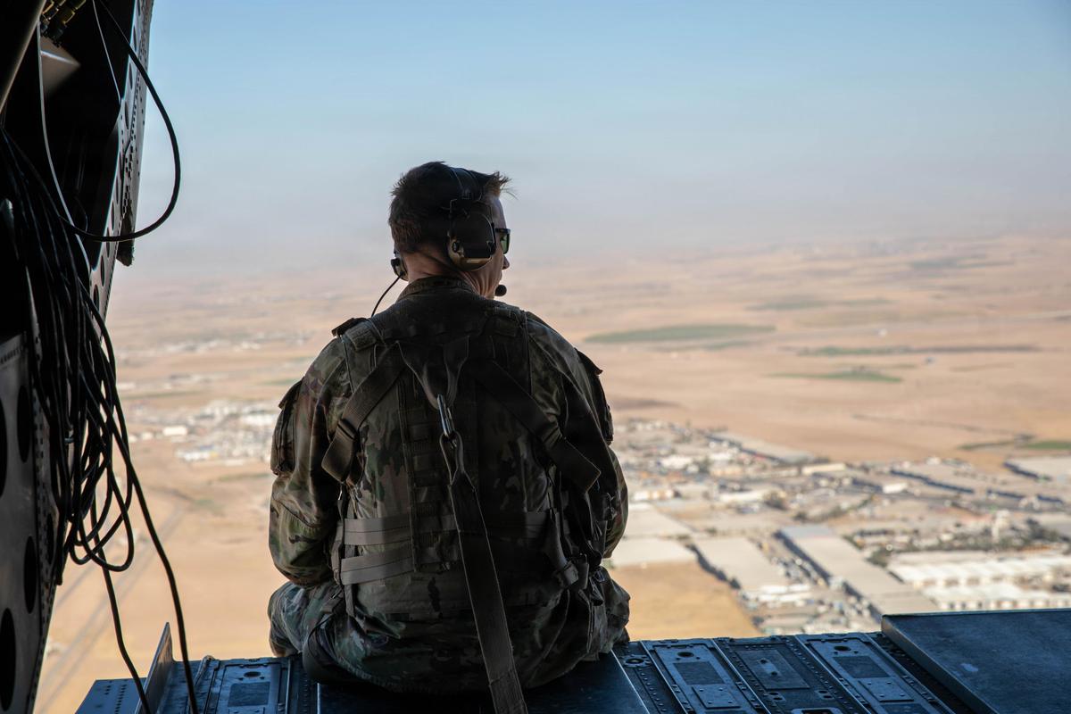 A US soldier sits looking out the back of a CH-47 helicopter as it flies in northern Iraq