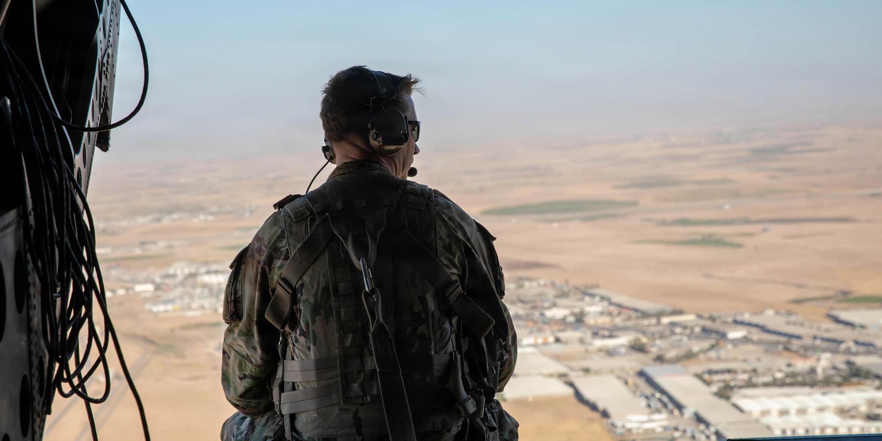 A US soldier sits looking out the back of a CH-47 helicopter as it flies in northern Iraq