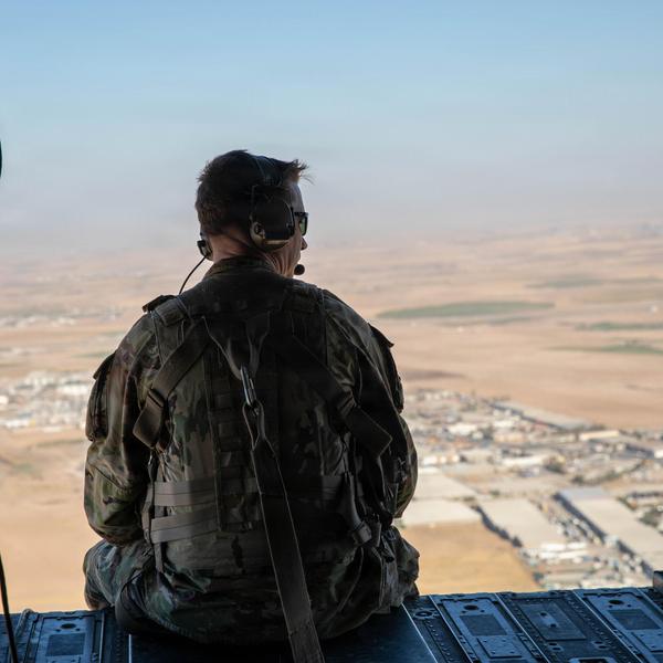 A US soldier sits looking out the back of a CH-47 helicopter as it flies in northern Iraq