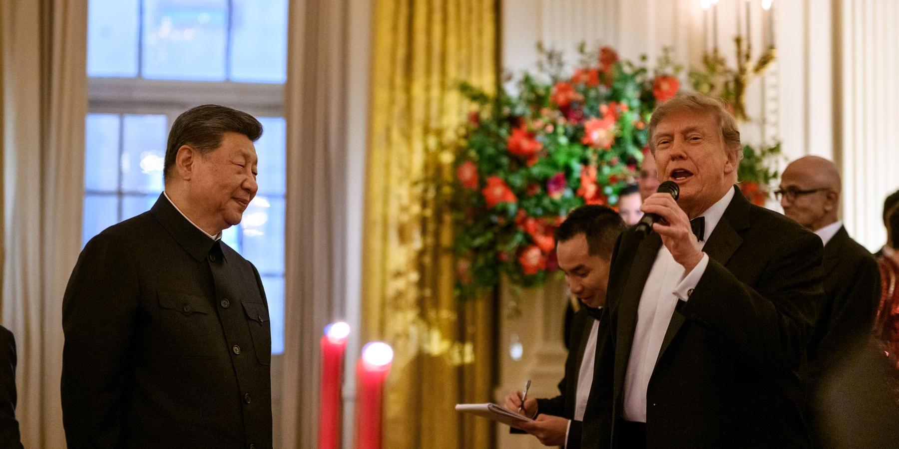 Donald Trump speaks into a microphone as Xi Jinping listens nearby