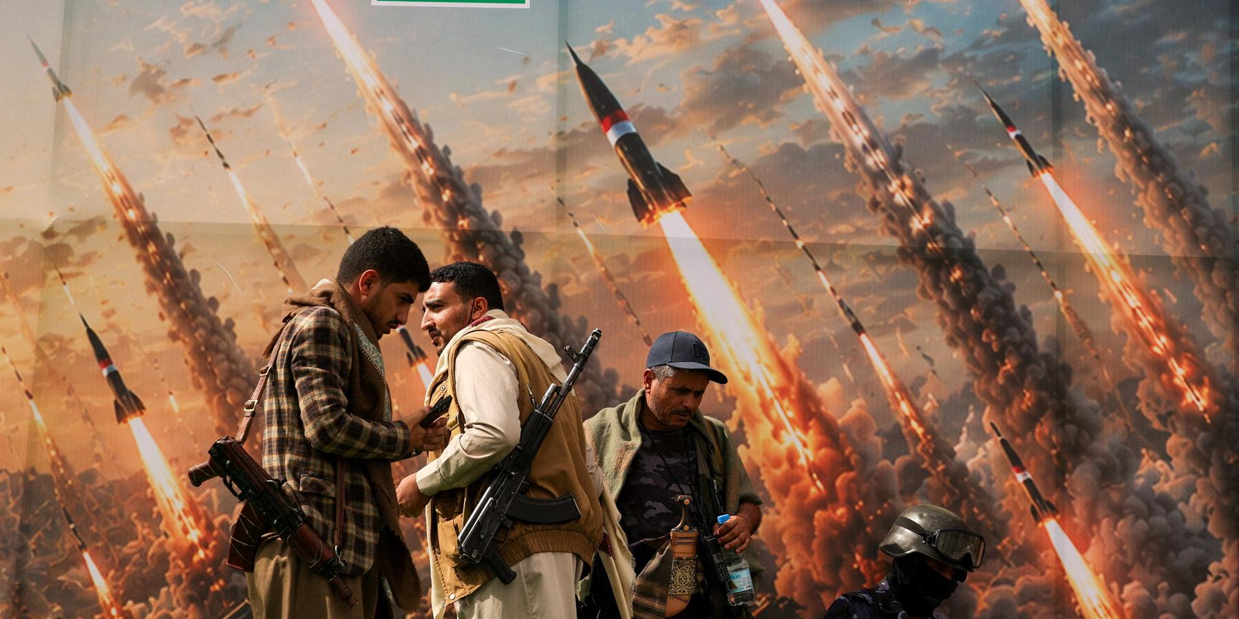 Houthi activists stand on a platform against a banner depicting Houthi missiles, at an anti-Saudi rally in Sanaa, Yemen