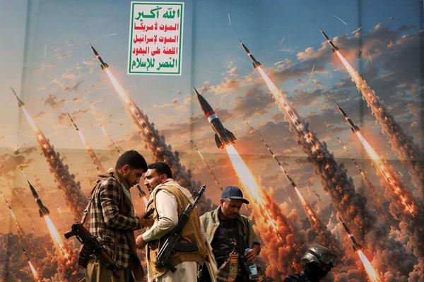 Houthi activists stand on a platform against a banner depicting Houthi missiles, at an anti-Saudi rally in Sanaa, Yemen