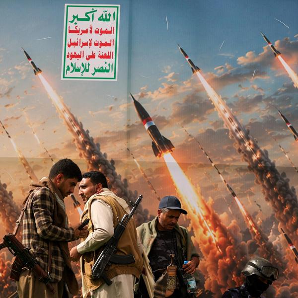 Houthi activists stand on a platform against a banner depicting Houthi missiles, at an anti-Saudi rally in Sanaa, Yemen