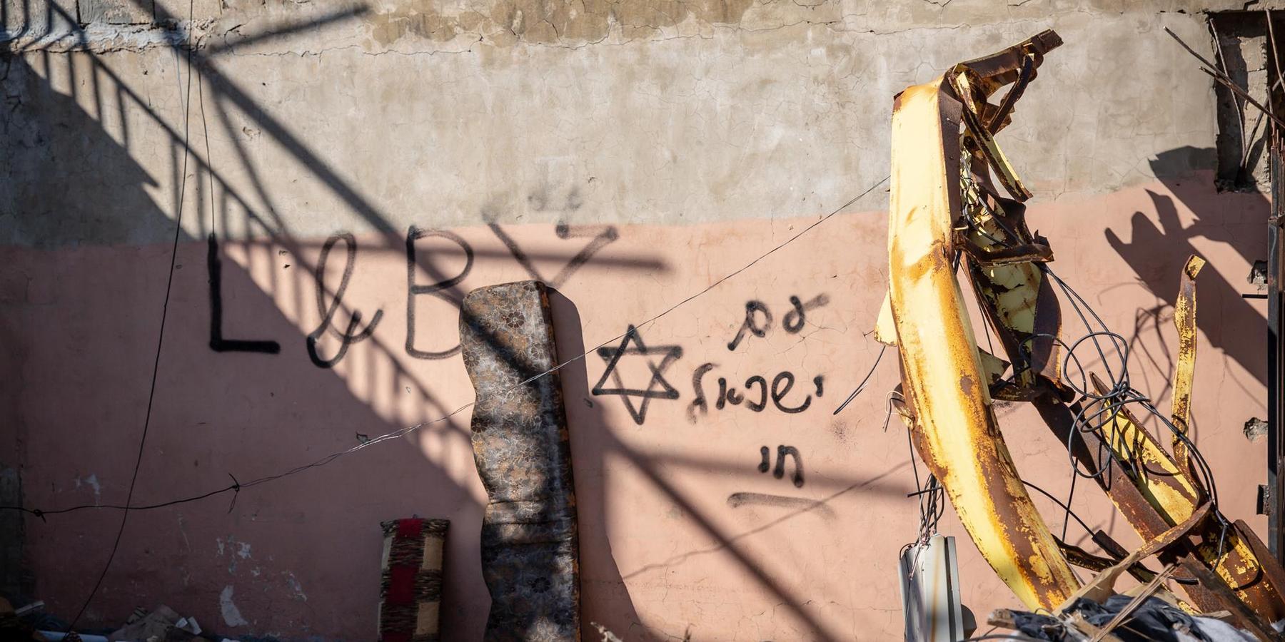 Hebrew-language graffiti and a Star of David can be seen in the village where Israeli soldiers had a presence following their invasion. A mass funeral for 95 people who died during the war between Israel and Hezbollah was held in Aitaroun, close to the Lebanon-Israeli border, on February 28, 2025. (Sally Hayden / SOPA Images via Reuters Connect)
