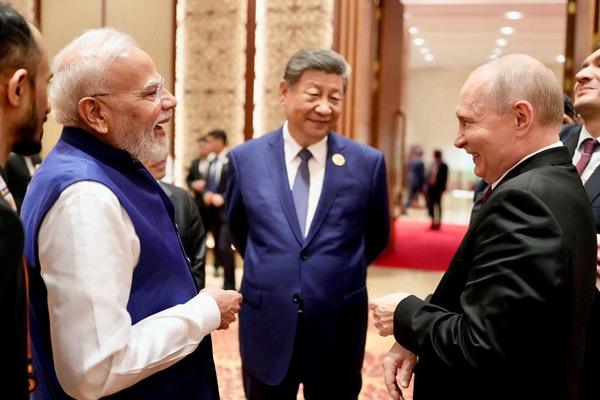 India's Prime Minister Narendra Modi shares a moment with Russian President Vladimir Putin as Chinese President Xi Jinping looks on during day two of the BRICS Summit in New Delhi