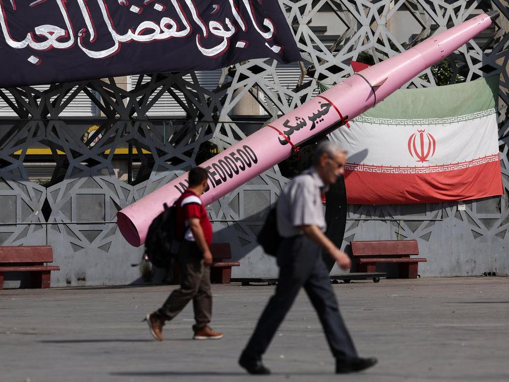 People walk next to a symbolic mockup of an Iranian missile and an Iranian flag at Imam Hussein Square in Tehran, Iran, on July 12, 2026.