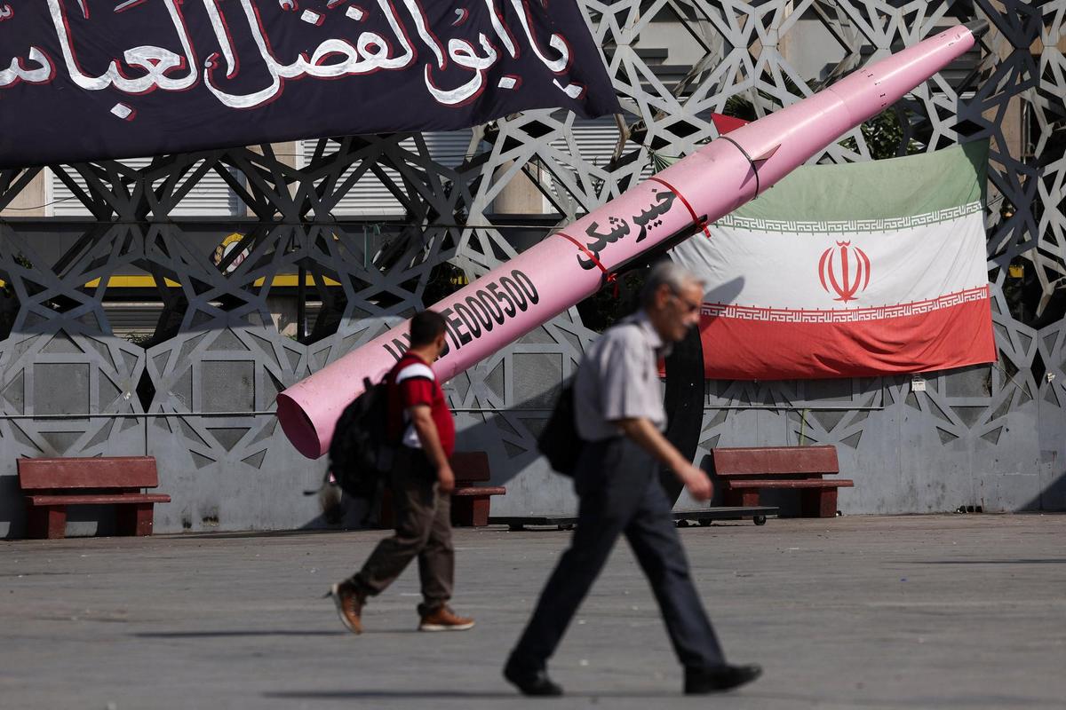 People walk next to a symbolic mockup of an Iranian missile and an Iranian flag at Imam Hussein Square in Tehran, Iran, on July 12, 2026.