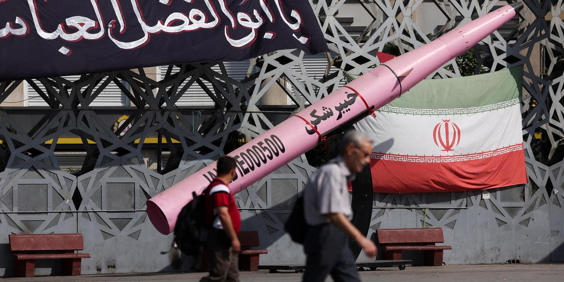 People walk next to a symbolic mockup of an Iranian missile and an Iranian flag at Imam Hussein Square in Tehran, Iran, on July 12, 2026.