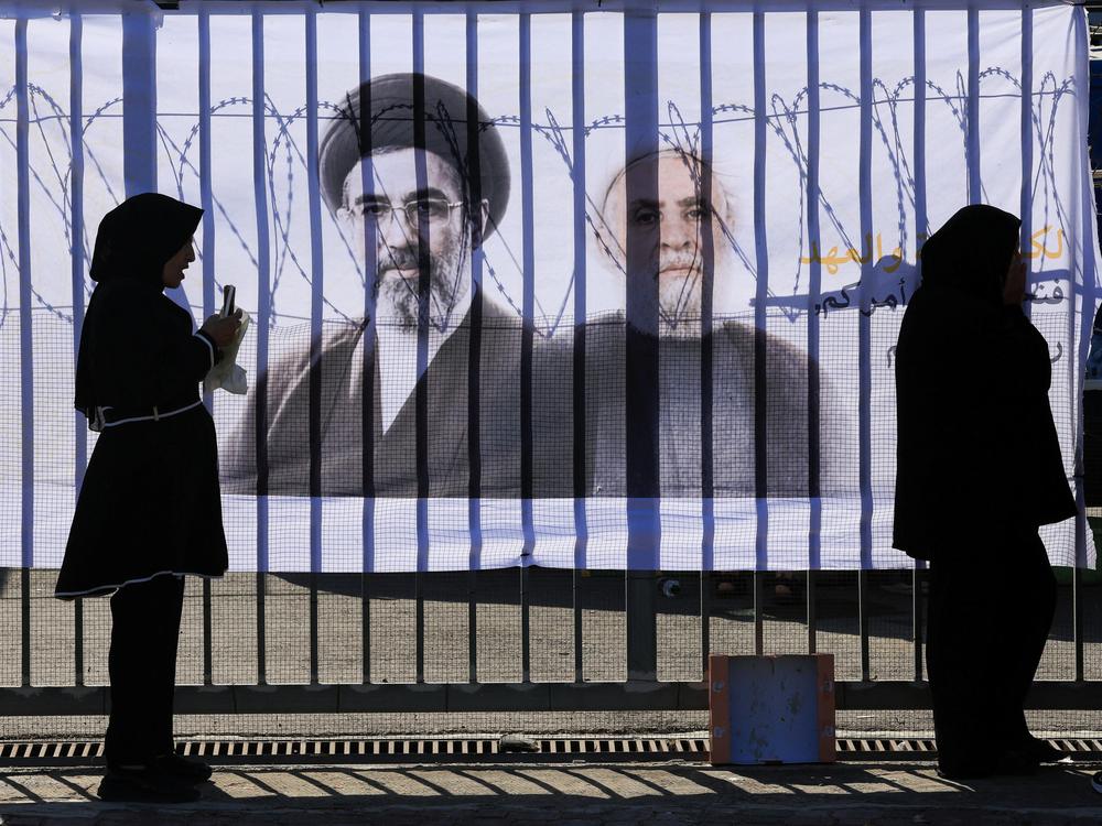 Shi'ite mourners stand in front of a banner with pictures of Hezbollah chief Naim Qassem and Iran's new Supreme Leader Mojtaba Khamenei, as they mark Ashura, the holiest day on the Shi'ite Muslim calendar, in the southern suburbs of Beirut
