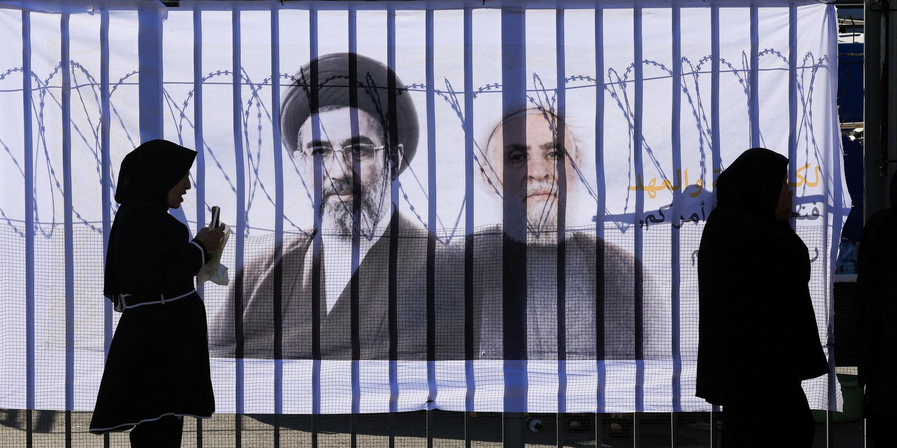 Shi'ite mourners stand in front of a banner with pictures of Hezbollah chief Naim Qassem and Iran's new Supreme Leader Mojtaba Khamenei, as they mark Ashura, the holiest day on the Shi'ite Muslim calendar, in the southern suburbs of Beirut