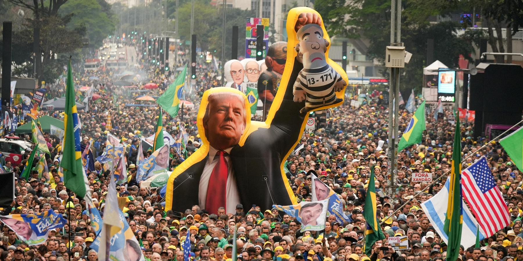 Supporters of Flavio Bolsonaro at a rally, with some carrying a large inflatable of Donald Trump