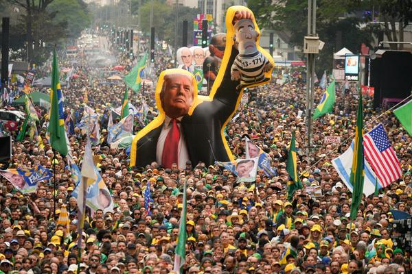 Supporters of Flavio Bolsonaro at a rally, with some carrying a large inflatable of Donald Trump